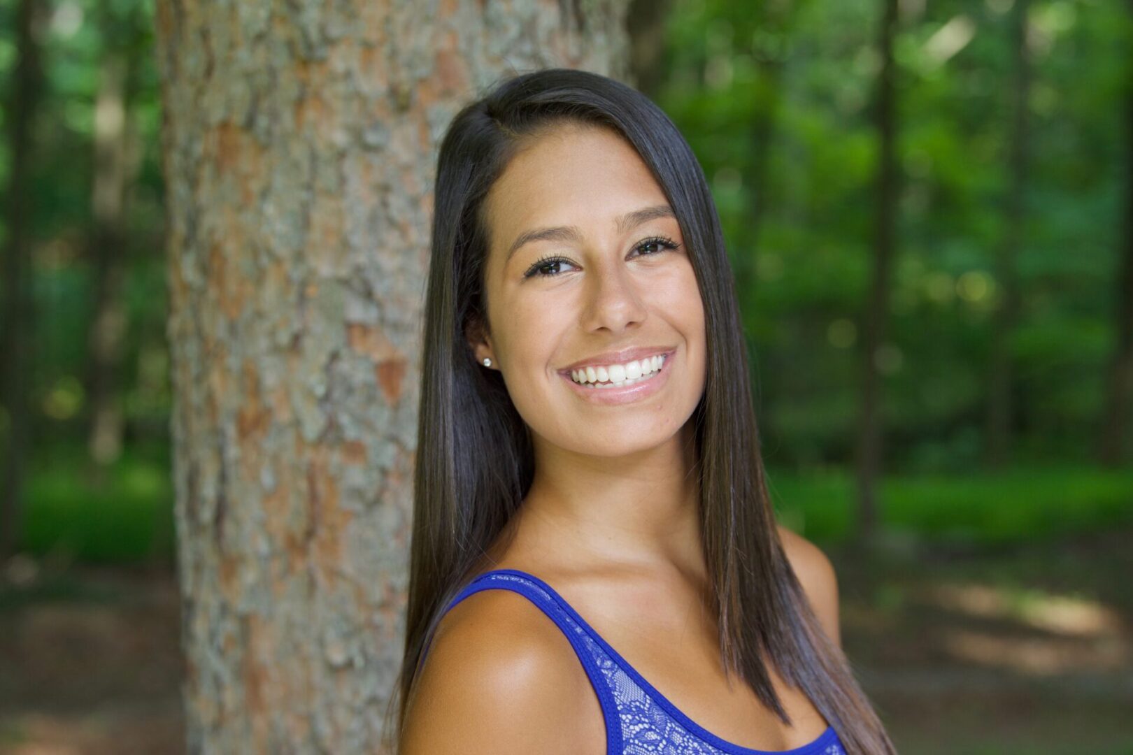 A woman smiling in front of a tree.