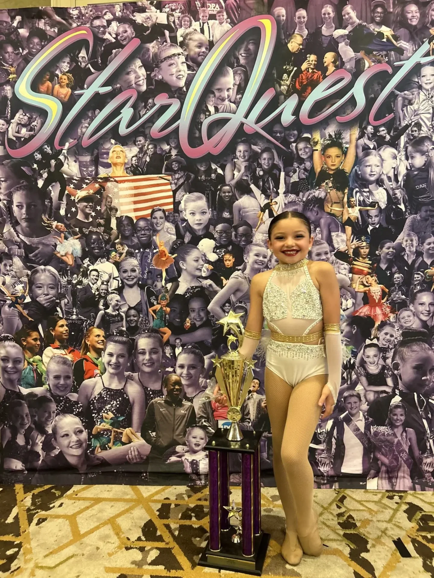 Young dancer posing with trophy in front of collage.