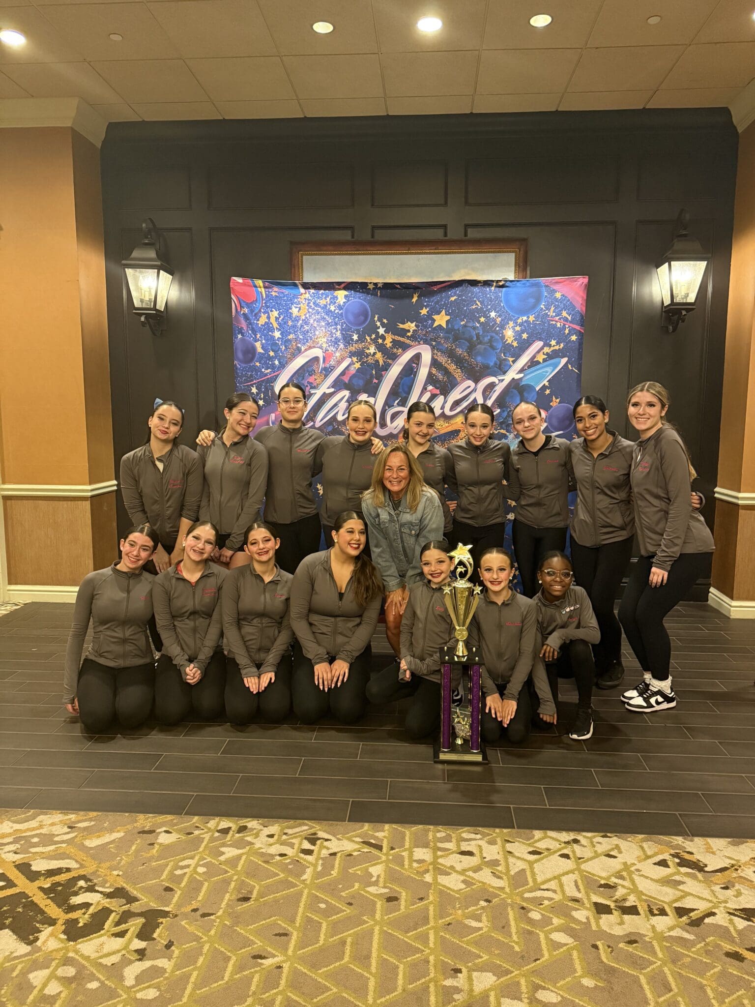 Group of young dancers posing together at a competition venue.