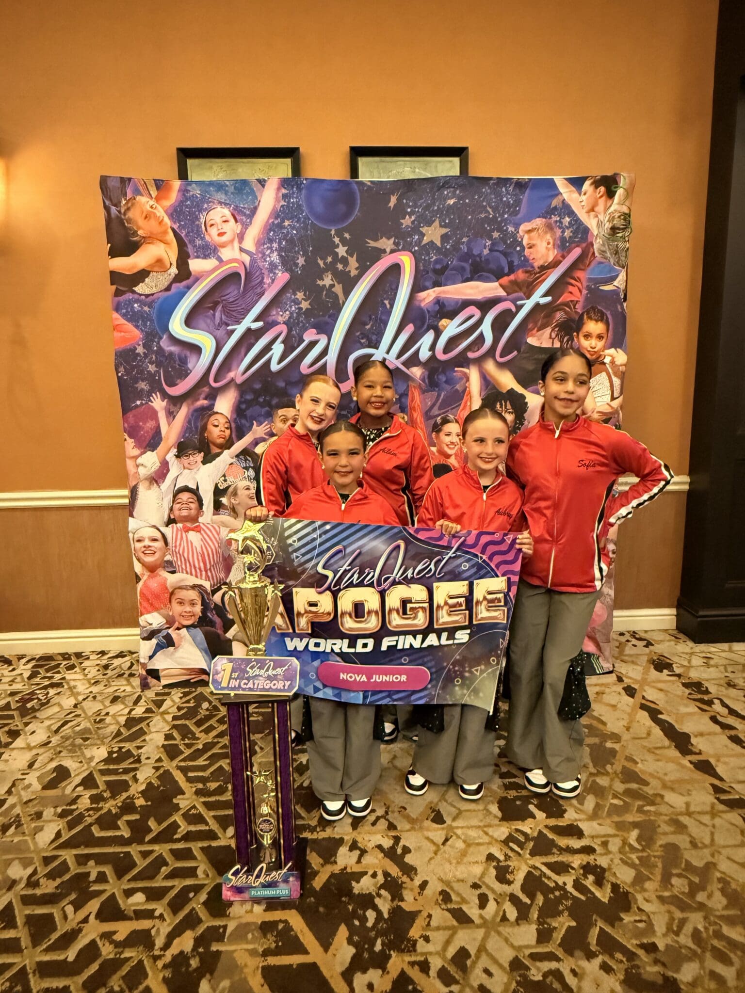 Youth dance team posing with trophy and banner