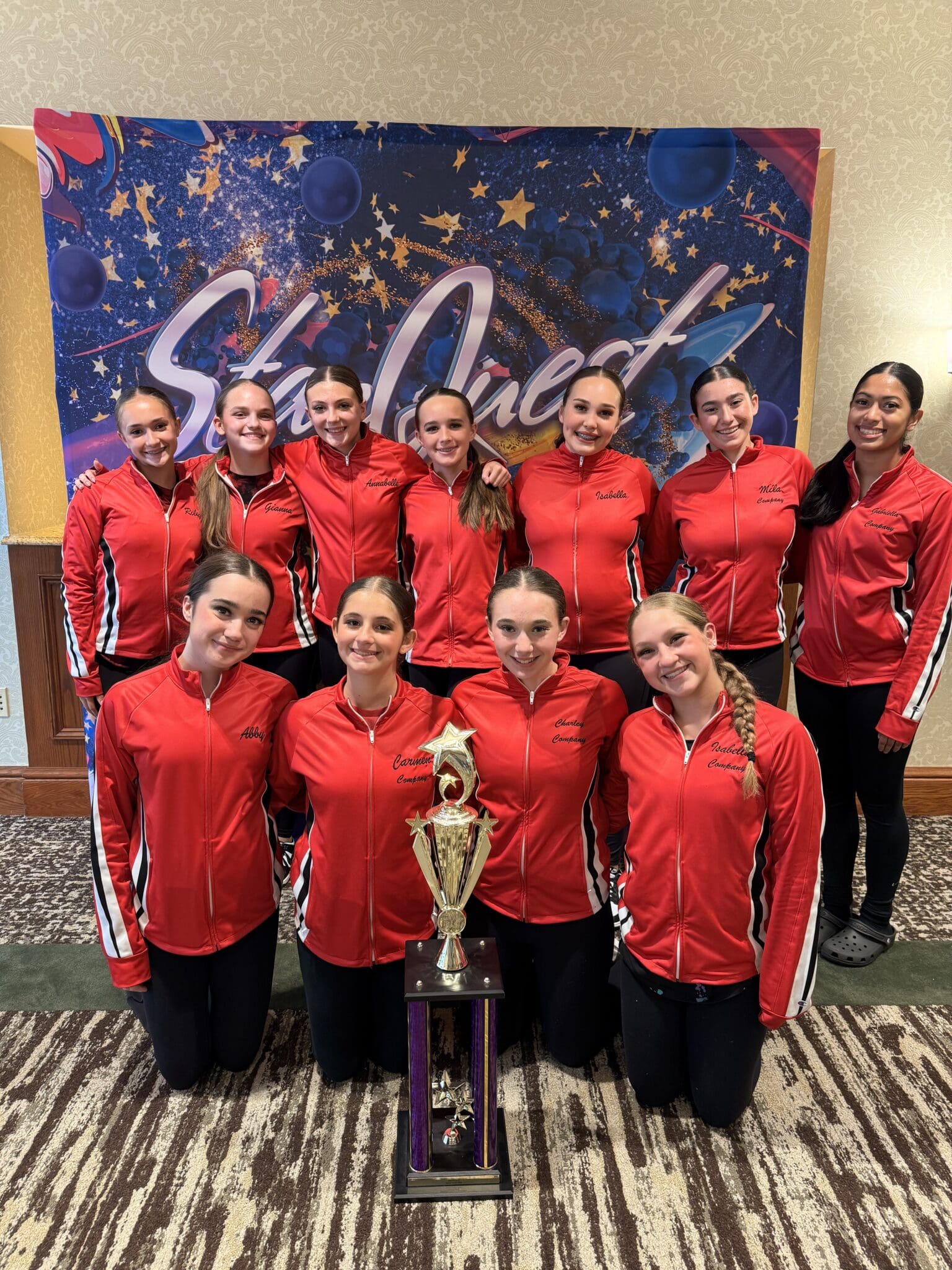 Dance team in red jackets holding trophy